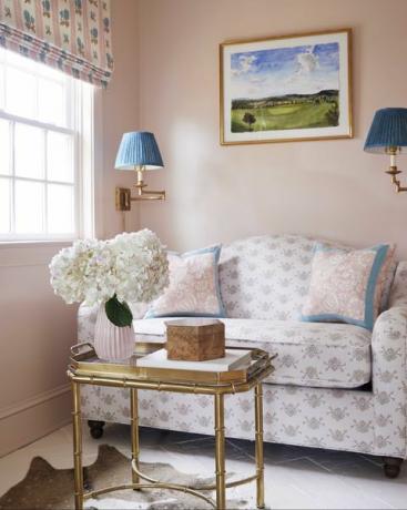 vaaleanpunaiset maalatut seinät, kultainen sohvapöytä, siniset lamput