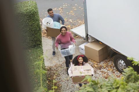 Perhe muutti uuteen taloon kuljettaen laatikoita liikkuvasta pakettiautosta