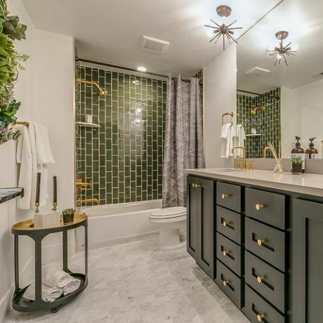 vihreä on teema tässä kauniissa kylpyhuoneessa, jossa on messinkiset hanat ja kalusteet