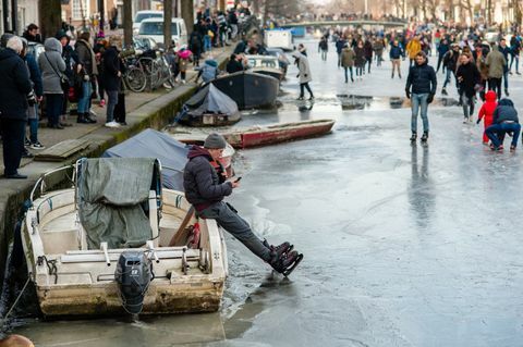 Kymmenet ihmiset luistella Amsterdamin kanavilla