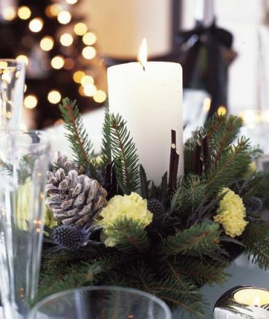 mustavalkoiset joulukoristeet, joissa on hopeaa ja koristeltua violettia kotiin, ruokapöytä kynttilän keskellä, valmistettu tuoreesta oksasta, männynkäpyistä ja neilikoista