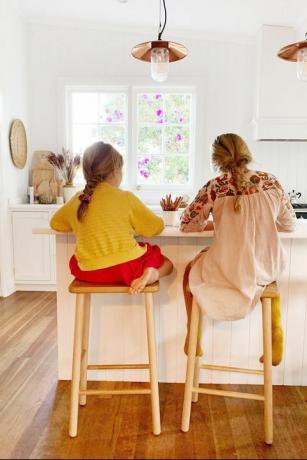 kaksi tyttöä tekemässä kotitehtäviä keittiön saarella