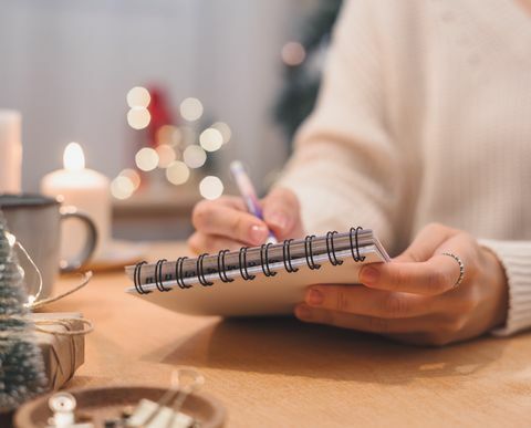 tavoitteet suunnitelmat tekevät ja toivelista uudenvuoden joulukonseptin kirjoittamiseen muistikirjaan nainen käsi kynä muistilehtiöön kotona talvipäivinä joulu