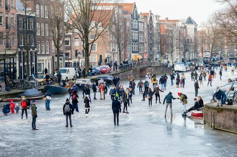 Kymmenet ihmiset luistella Amsterdamin kanavilla