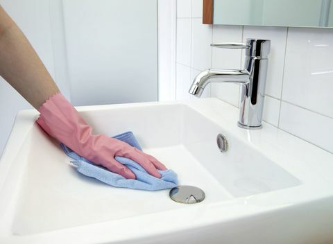 Pesualtaan puhdistus: Nainen, joka puhdistaa pesualtaan mikrokuituliinalla ja käsineillä