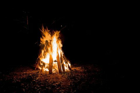 ulkona nuotio korkeilla liekeillä, jotka on sisällytetty teepee-muotoisiin levyihin