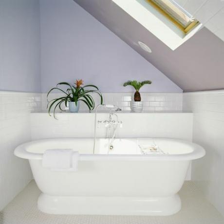 kylpyamme kattoikkunan alla ullakkokylpyhuoneessa, jossa lila violetit seinät