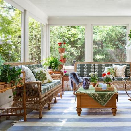 verhoiltu kuistilla, sinivalkoinen raidallinen matto, korituolit ja sohva vihreillä ja valkoisilla tyynyillä, sisäkasveja