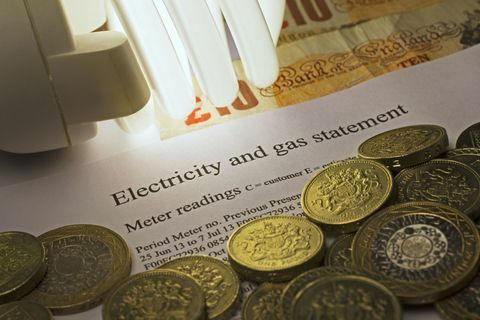 Sähkö- ja kaasuilmoitus energiansäästölampulla ja Ison-Britannian punnan seteleillä ja kolikoilla.