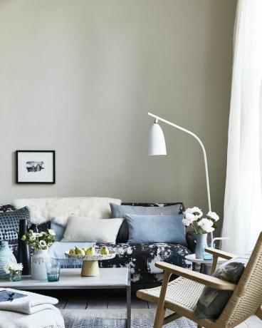 neutraali olohuone, olohuone tyynyillä sinisellä kuviollisella sohvalla, valkoinen lattiavalaisin taivutettuna sohvan päällä pisaroiden, täplät ja roiskekuviot antavat nykyaikaisen impressionistisen ilmeen ja rento